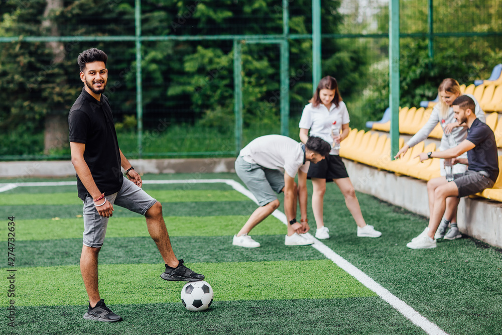 Full length view of athletic african american soccer player  staying with ball on green field.