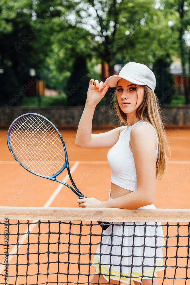 Portrait of a young woman playing tennis on a dross field..