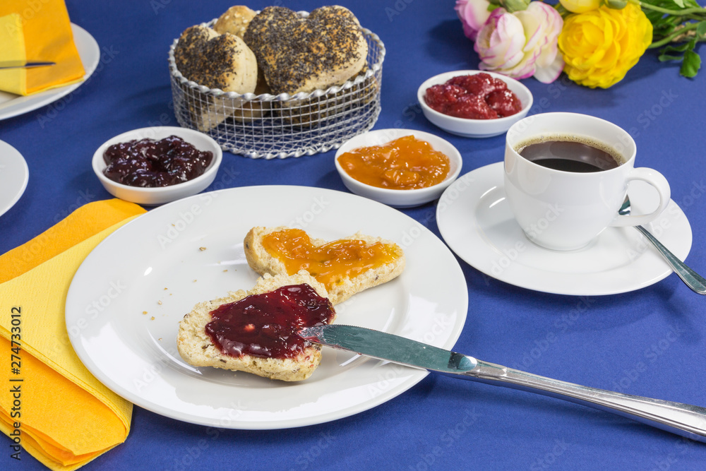 breakfast table with freshly baked heart shaped buns, different jams and coffee breakfast table with freshly baked heart shaped buns, different jams and coffee