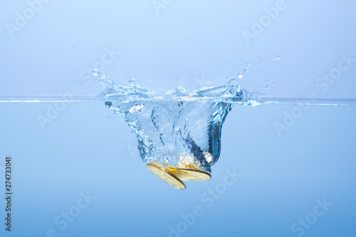 Coins in the water. Water splash from falling gold coins. Golden coins falling in water with splashes.
