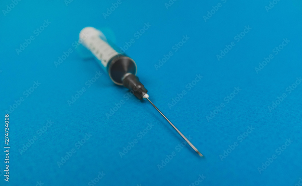 medical syringe with a needle lying on a blue background medical syringe with a needle lying on a blue background