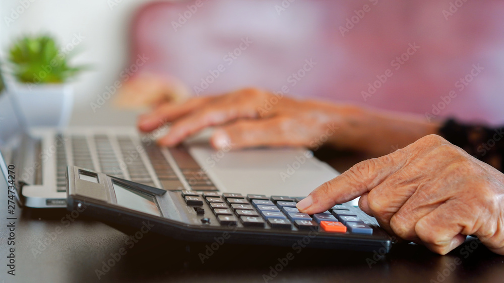 close up grandmother hand press on calculator for counting about monthly expense or planning money management after retired concept close up grandmother hand press on calculator for counting about monthly expense or planning money management after retired concept