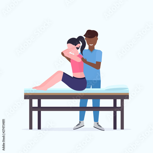 woman patient sitting on massage table african american masseur therapist doing healing treatment massaging injured back manual sport physical therapy rehabilitation concept full length
