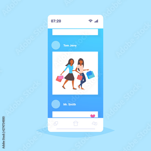 women holding colorful paper bags couple girls carrying purchases walking together big sale shopping concept smartphone screen mobile application flat full length