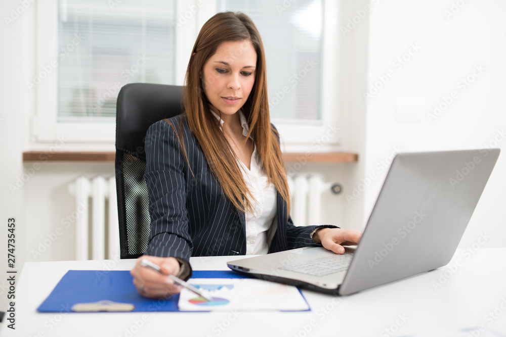Woman using a laptop computer while writing