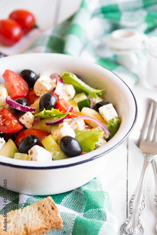 Delicious greek salad with feta cheese and olives in a white bowl Delicious greek salad with feta cheese and olives in a white bowl