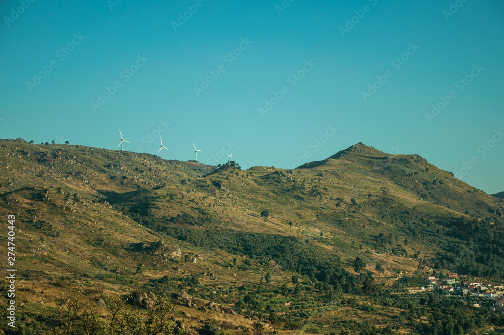 Naklejka premium Hilly landscape covered by rocks and some wind turbines