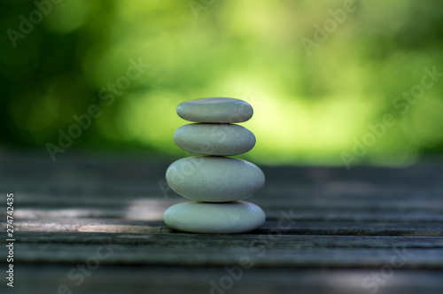 Harmony and balance  cairns  simple poise pebbles on wooden table  natural green background  simplicity rock zen sculpture