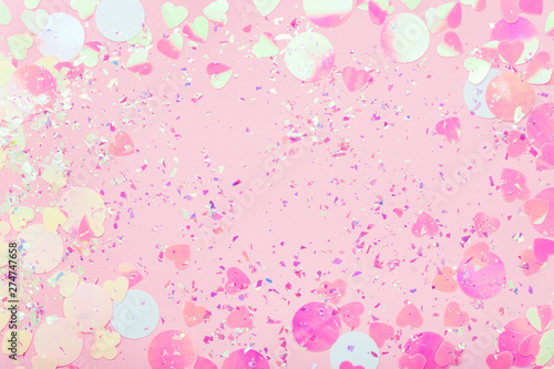 Colorful Confetti and sparkles on pink pastel trendy background. Festive frame, holiday backdrop. Flat lay, copy space.