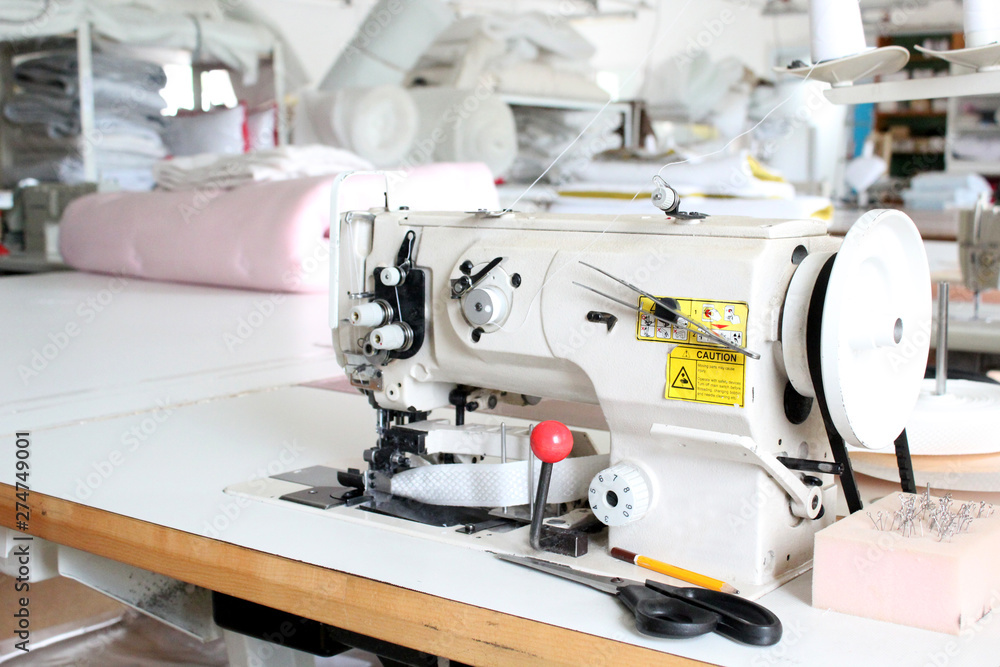 Professional sewing machine overlock in the workshop. Equipment for edging, hemming or stitching clothes in a tailor shop.