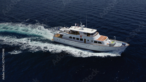 Aerial drone photo of luxury yacht cruising deep blue sea in Mediterranean Aegean island destination located in Greece