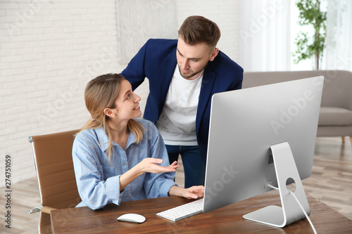 Man helping his colleague work with computer in office