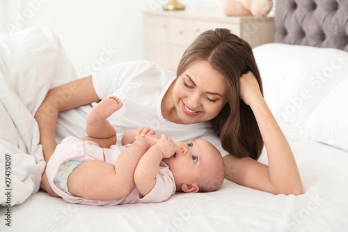 Portrait of mother with her cute baby lying on bed indoors