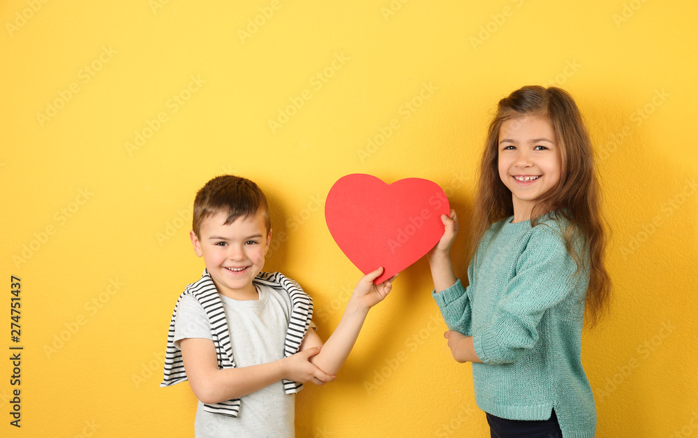 Happy children holding paper heart on color background Happy children holding paper heart on color background