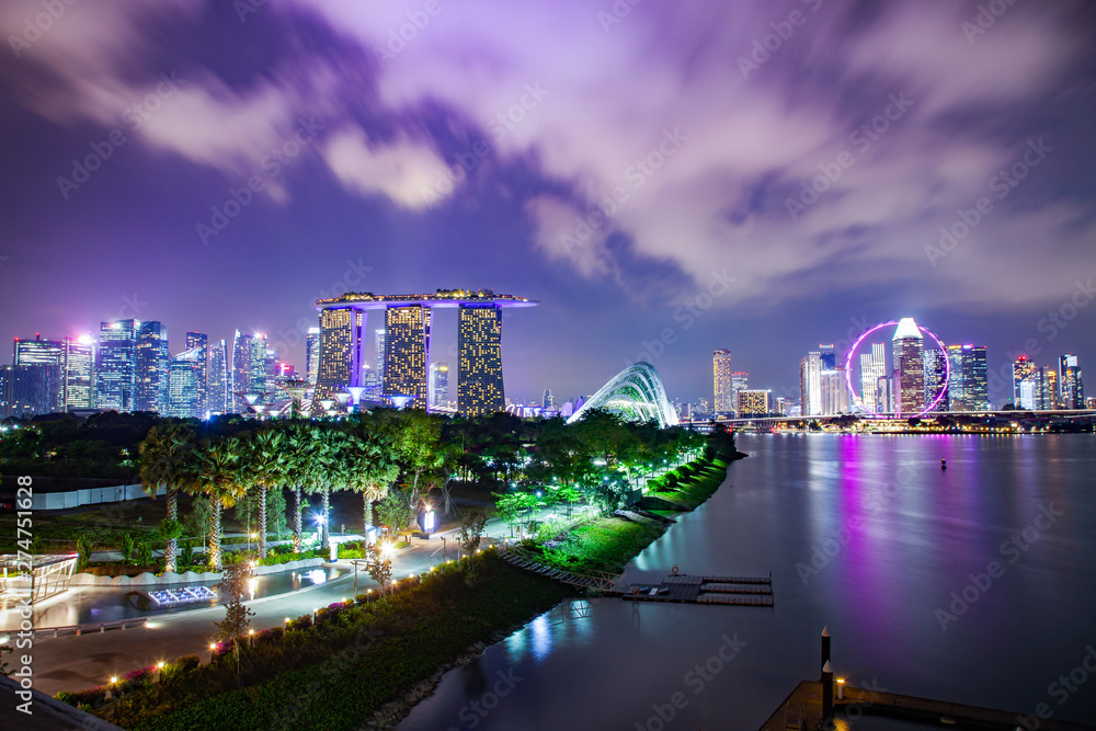 Fototapeta premium SINGAPORE, SINGAPORE - MARCH 2019: Vibrant Singapore skyline with Marina Bay Sands, Gardens by the bay with cloud forest, flower dome and supertrees at sunset. Top view from marina barrage