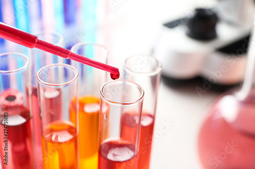 Dripping reagent into test tube with sample in chemistry laboratory, closeup. Space for text