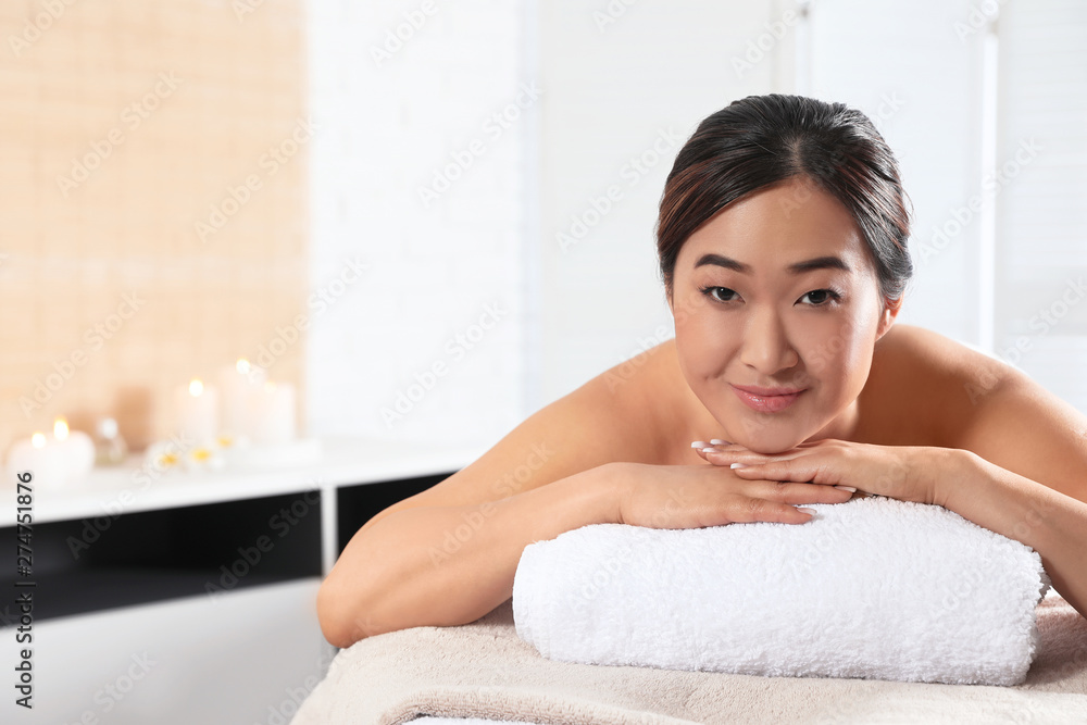 Beautiful Asian woman lying on massage table in spa salon. Space for text Beautiful Asian woman lying on massage table in spa salon. Space for text