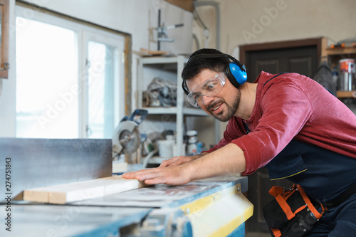 Mature man using wood working machine at carpentry shop