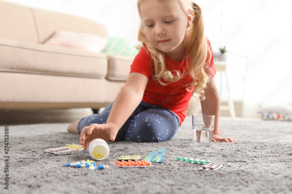 Little child with many different pills on floor at home. Danger of medicament intoxication Little child with many different pills on floor at home. Danger of medicament intoxication