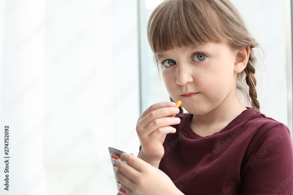 Little child taking pill indoors, space for text. Danger of medicament intoxication Little child taking pill indoors, space for text. Danger of medicament intoxication
