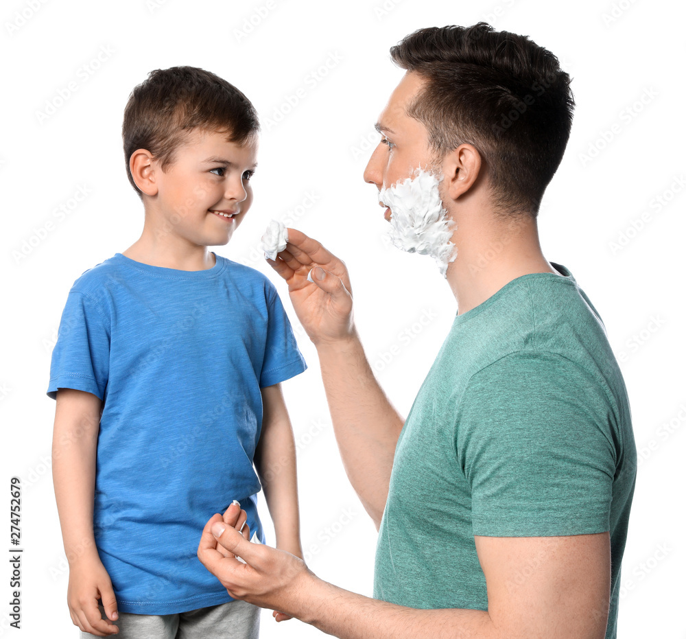 Dad applying shaving foam onto son's face against white background Dad applying shaving foam onto son's face against white background