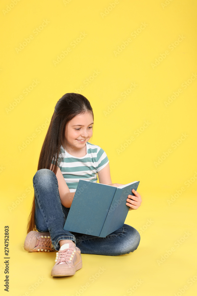Cute little girl reading book on color background, space for text Cute little girl reading book on color background, space for text