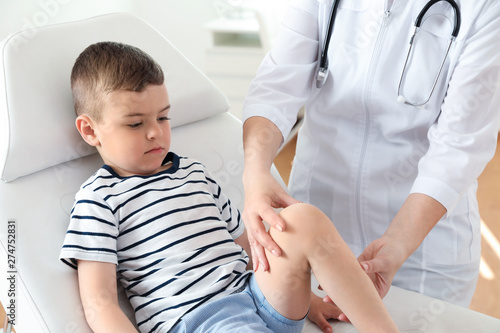 Doctor examining little patient with knee problems in clinic