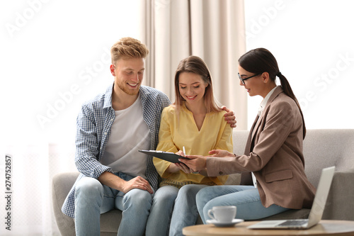 Obraz na plátně Young couple signing contract with female insurance agent in office