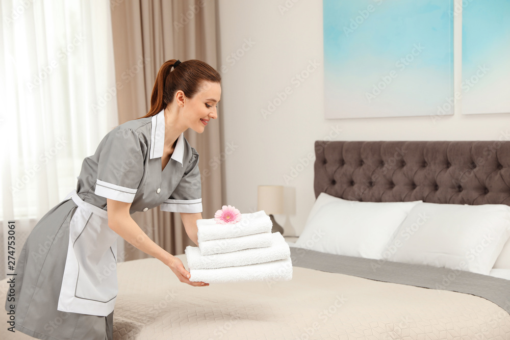 Chambermaid putting fresh towels on bed in hotel room. Space for text Chambermaid putting fresh towels on bed in hotel room. Space for text