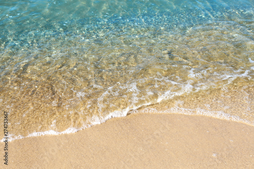 View of sea water and beach sand on sunny day