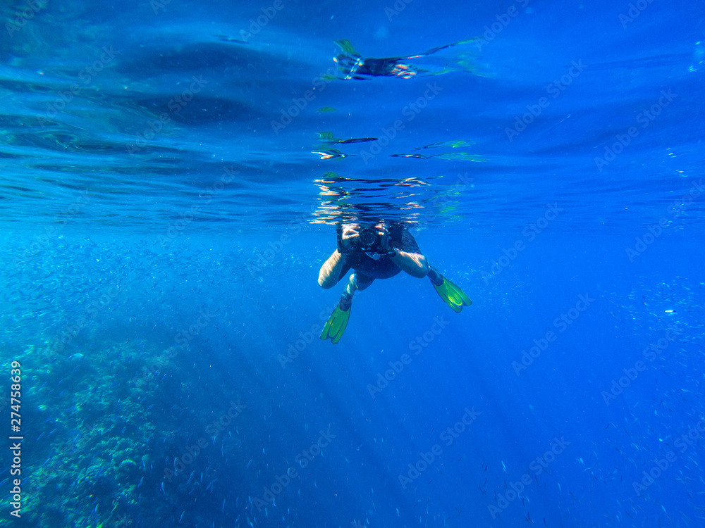 Man with underwater photocamera in blue sea water. Snorkeling in tropical seaside. Summer vacation in exotic island
