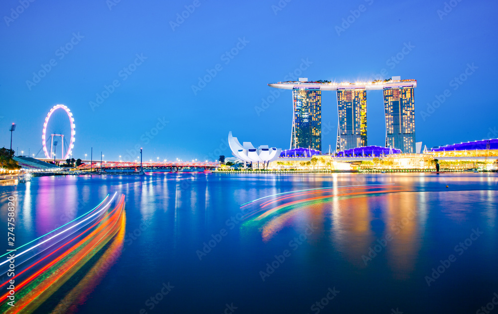Fototapeta premium SINGAPORE, SINGAPORE - MARCH 2019: Skyline of Singapore Marina Bay at night with Marina Bay sands, Art Science museum and tourist boats