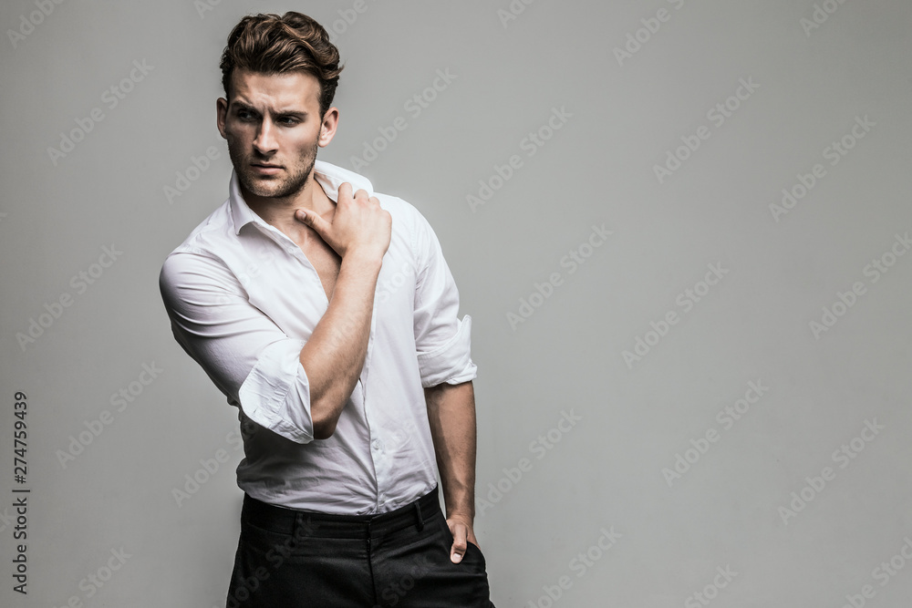 Portrait of young and handsome model in a white shirt. Studio shot. Copy space. - obrazy, fototapety, plakaty 