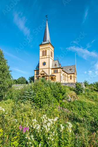 View at Vagan Church  called Lofoten Cathedral  from the slope covered with green plants and flowers. Kabelvag village in Austvagoya island  Nordland  Northern Norway.