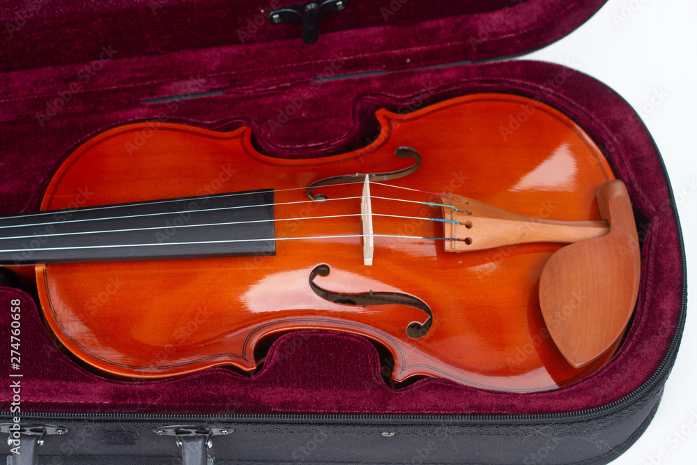 Part of an orange violin in a burgundy velvet case. Part of an orange violin in a burgundy velvet case.