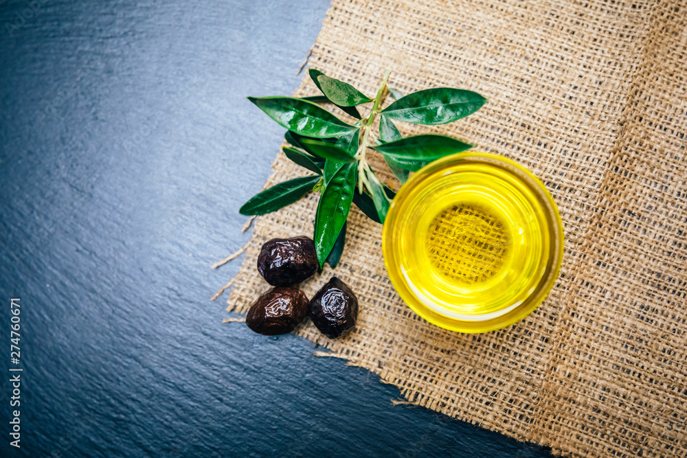 Organic, natural and healthy cold pressed olive oil on wooden table. Virgin italian or spanish olive oil in a bowl for healthy vegetarian or vegan breakfast close up concept image.