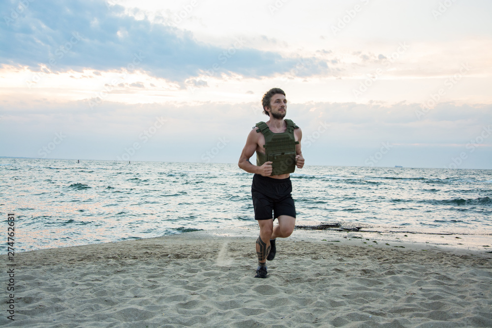 Young bearded athlete training outdoor with weighted vest, exercise with military plate carrier Young bearded athlete training outdoor with weighted vest, exercise with military plate carrier
