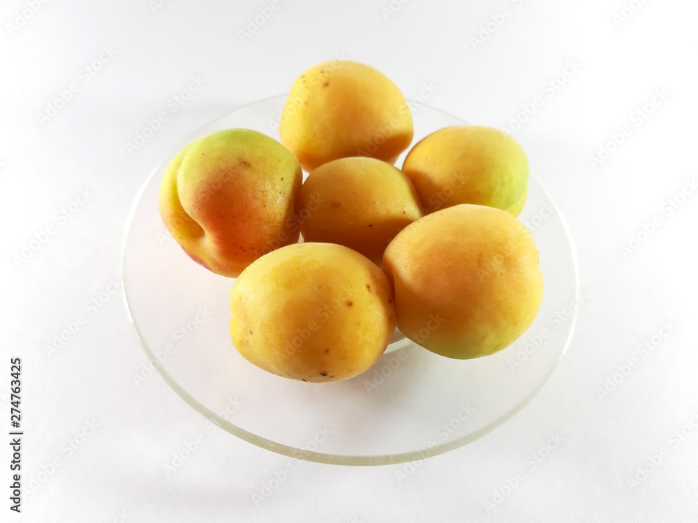 Whole apricots on a plate. Isolated photo. Yellow ripe round apricots