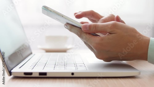 Woman freelancer working on laptop at home-office. Close up of female hands with mobile phone. Businesswoman sending message to colleague via smartphone at work. Camera trucking