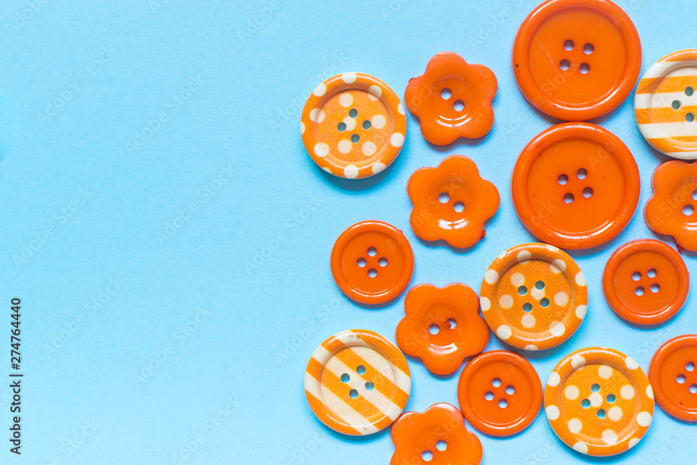 Fototapeta premium Various orange sewing buttons on blue background
