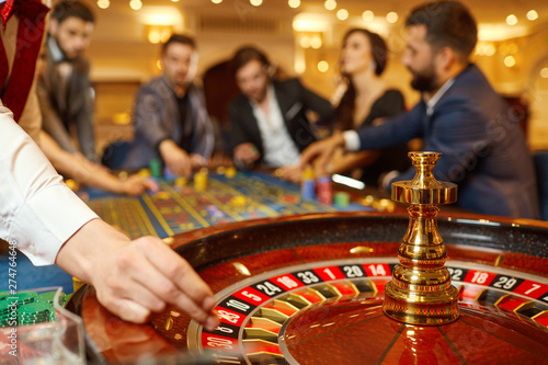 The croupier holds a roulette ball in a casino in his hand.