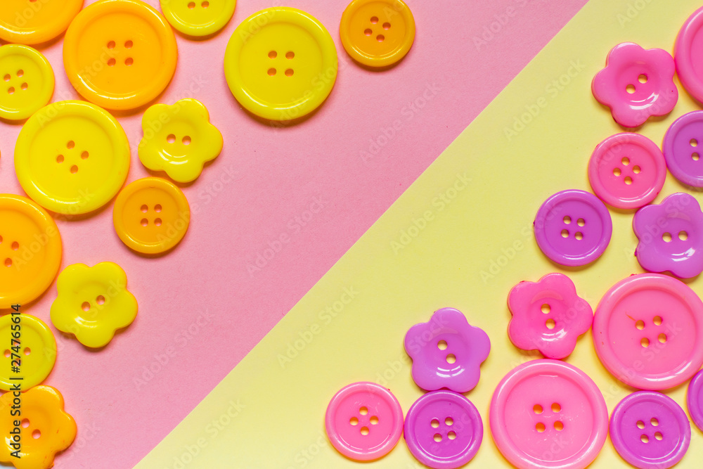 Various pink and yellow sewing buttons on light yellow and pink background with place for text Various pink and yellow sewing buttons on light yellow and pink background with place for text