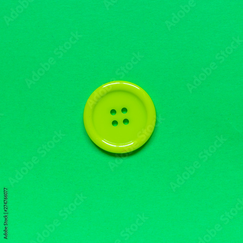 Single green sewing button on green background