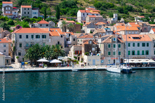 Old city of Vis viewed from the sea entering the harbor with old stone houses with red rooftops and sailing boats anchored in summer, Vis island, Croatia