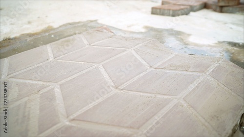 a worker laying red concrete paving blocks. Lay paving stones