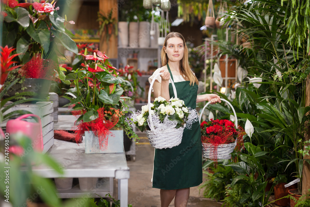 Portrait of skilled woman florist arranging flowers in pots at flower shop