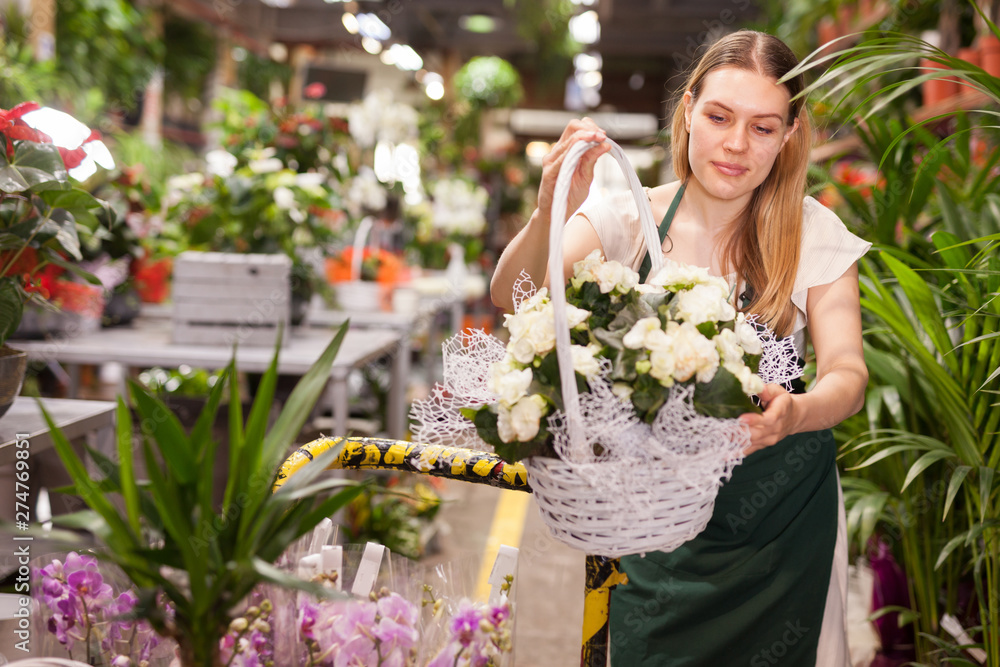 Fototapeta premium Female florist delivering pots of flowers on a pushcart