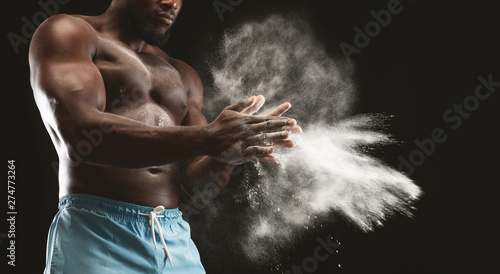 Muscular afro man clapping hands with magnesium powder