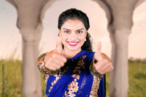 Smiling Indian woman shows thumbs up at home