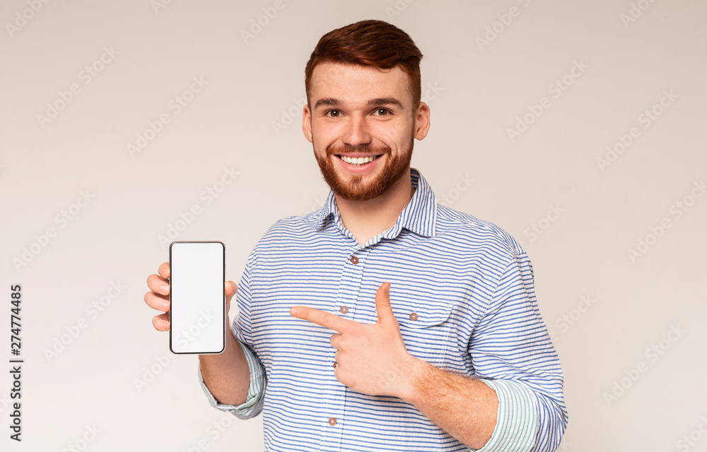 Smiling millennial man holding latest slim cellphone Smiling millennial man holding latest slim cellphone